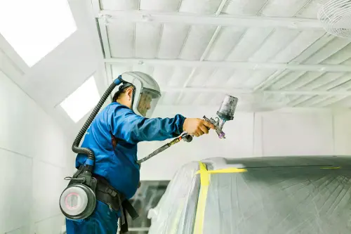 Caliber Collision Paint Tech painting repaired car.