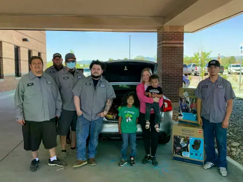 A deserving family and the Collision Team behind the vehicle restoration work at an NABC Recycled Rides giveaway event.